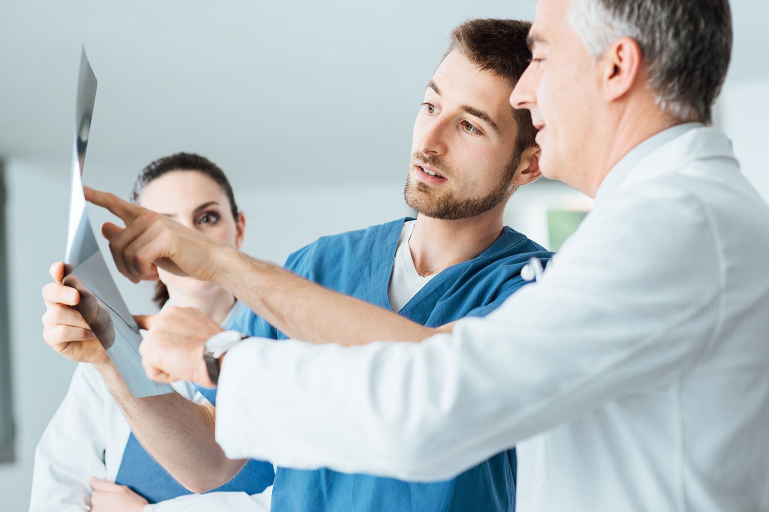 Ein Arzt prüft mit seinem Team Röntgenaufnahmen eines Patienten